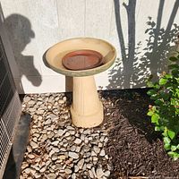 Full view of resin bird bath showing beige body, green trim, and terracotta insert