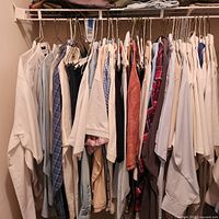 Full closet rod view of assorted men’s shirts on hangers