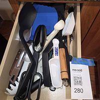Drawer view with assorted utensils including ladle, shears, Ninja spatula, scoop and trivet
