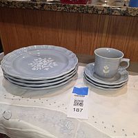 Stack of five dinner plates left, mug on four saucers right