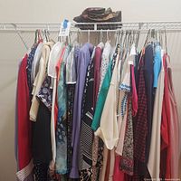 Full rack of assorted plus size tops and sweaters on hangers