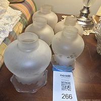 Five matching frosted etched glass shades grouped on table
