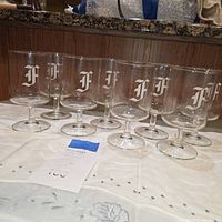 Full set of 8 clear glass goblets with etched H monogram displayed on table