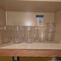 Eight faceted clear glass tumblers on shelf