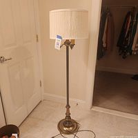 Full view of brass finish floor lamp with cream shade