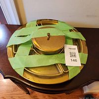 Top view of assembled brass lazy Susan with tape securing lid and inserts