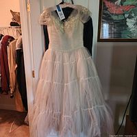 Front view of full ivory tulle ball gown wedding dress hanging on door