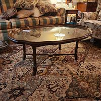 Full view of oval glass-top wood coffee table in room setting