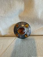 front view showing engraved silver-plated brooch and amber stones