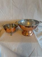 Both copper-plated colanders side by side