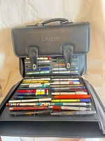 Closed Magnus Pen branded folio showing interior panels filled with assorted pens and pencils