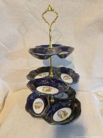 Full view of assembled three-tier tray showing cobalt plates, medallions, and brass handle
