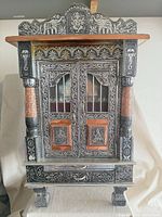 Front view showing embossed metal exterior, doors, legs and drawer
