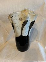 Full front view of ruffled beige and black glass vase