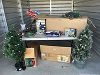 Overall lot on table: two trees, lights, wrapping paper, boxes