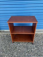 Front view of cherry veneer 2-tier shelf showing top, middle and lower shelves and casters
