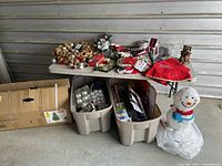 Full lot showing table with decorations, tree box, storage totes and lighted snowman