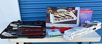 Lot overview on folding table showing all boxed items, mitt, pads, utensil case