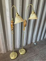 Full view of both brass floor lamps standing side by side
