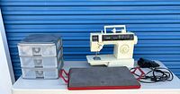 Full lot showing sewing machine, storage drawers, pressing pad, foot pedal and cords on table