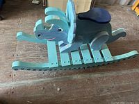 Left side view of wooden elephant rocking toy showing rocker base, body, and seat