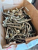 Cardboard box filled with numerous silver-tone pull handles and some knobs