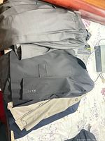 Stacked view of multiple jackets showing black, beige plaid and navy pieces