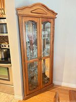 Front view of wood corner display cabinet with glass doors and interior shelves
