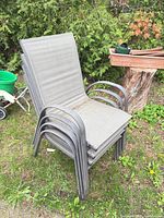 Front angled view of stack of four grey sling patio chairs
