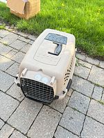 Overall view of tan plastic carrier on patio