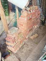 Stack of red clay bricks against wall showing quantity and condition