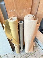 Front view of three paper rolls leaning against wall