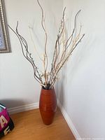 Full view of vase with branches against wall, showing size and shape