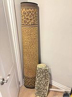 Rolled cheetah print rug standing upright beside rolled runner