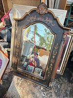 Full view of arched black framed mirror with gold stenciling