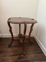 Three-quarter view of wood side table showing clover top, legs, lower shelf