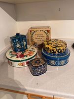 Group of six decorative tins displayed on countertop