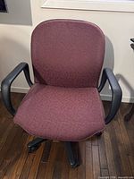 Front view of burgundy swivel office chair showing seat, backrest, and armrests