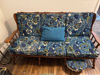 Front view of wooden sofa with floral cushions and footstool