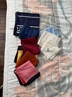 Full set of assorted handkerchiefs and pocket squares laid out on bed showing colours, patterns and monogram