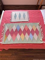 Two small flatweave rugs laid out to show patterns, colours and fringe