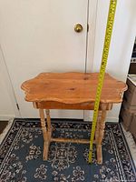 Front view of wooden side table with measuring tape showing height