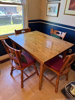 Overall view of wooden dining table with two of the four matching chairs