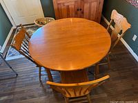 Round wooden dining table with three matching chairs