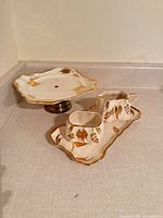 Overall view of four porcelain pieces showing gilt floral design