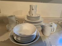 Full set stacked on counter showing plates, bowls, cups, creamer, sugar bowl