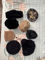 All eight hats arranged on bed for overview