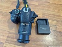 Top view of Nikon D3400 with attached 18-55mm lens and Nikon MH-24 charger