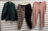All three clothing items hanging: green jacket, two-tone joggers, pink pants