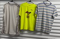 Three shirts hanging: grey long-sleeve, neon yellow event tee, striped tee